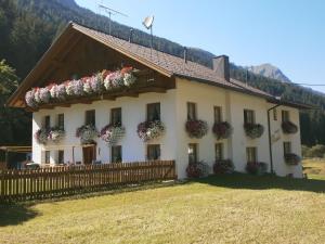 a large white house with flowers on the windows at Haus Bödele in Sankt Leonhard im Pitztal