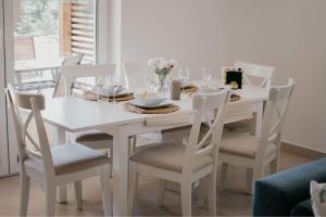 a white dining room table with white chairs at Green House Relax in Płaska