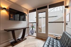 a living room with a couch and a television and a staircase at Midtown Hotel Royal Room in Amsterdam