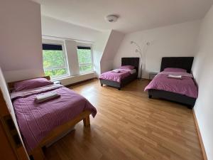 two beds in a room with purple sheets and wood floors at Großes Apartment im DG in Leipzig