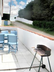 einen Grill auf einer Terrasse mit Stühlen und einem Tisch in der Unterkunft Maison d'une chambre avec terrasse amenagee et wifi a Noirmoutier en l'Ile in Noirmoutier-en-l'lle