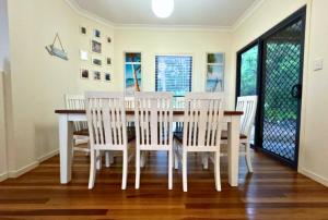 une salle à manger avec une table et des chaises blanches dans l'établissement Our Beach House K'gari, à Fraser Island