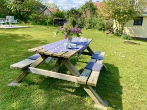 una mesa de picnic de madera con un jarrón de flores. en Ferienwohnung an der Schlei, en Fleckeby