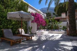 a patio with a chair and an umbrella and flowers at Kassandra Boutique Hotel in Oludeniz