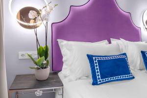 a bed with white pillows and a purple headboard at Hotel Casa Palacete Tablas in Granada