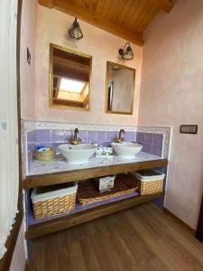 La salle de bains est pourvue de 2 lavabos et d'un miroir. dans l'établissement Casa Rural Lucia, à La Horcajada