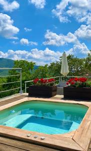 a swimming pool on a deck with flowers and an umbrella at Agriturismo Vezzano in Chiusi della Verna
