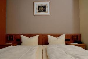 two beds with white sheets and a picture on the wall at Weinhaus Hotel zum Josefshof in Graach