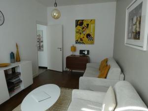ein weißes Wohnzimmer mit einem Sofa und einem Tisch in der Unterkunft La réserve à bonheurs in Les Sables-dʼOlonne