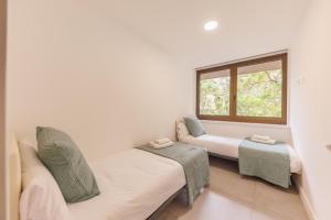 Habitación con 2 camas y ventana en Bravissimo Turbau Entresol B, with 3 bedrooms en Girona