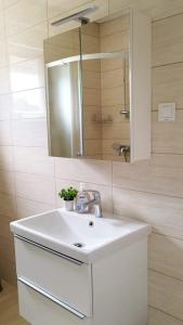 uma casa de banho com um lavatório branco e um espelho. em Apartmani Franka em Privlaka