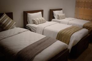 a room with three beds with white sheets at Xefan Hotels in Karachi