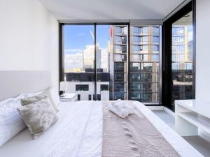 a bedroom with a white bed with a large window at Pride Manor South Yarra in Melbourne