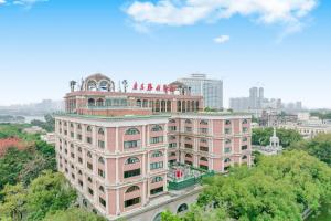 广州Guangdong Victory Hotel的一座粉红色的大楼，楼上有人