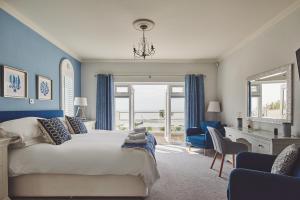 a bedroom with a bed with blue walls and a desk at Sun Beach House in Middleton-on-Sea