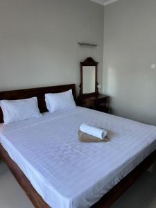 a bed with a white blanket and a towel on it at Simple Homestay Balangan in Jimbaran