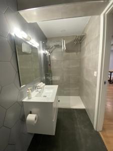 Baño blanco con lavabo y espejo en La Casa de Carola, en Bilbao