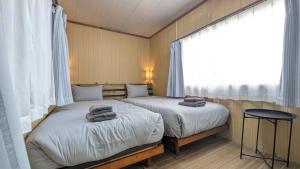 two twin beds in a room with a window at 与那国むんぶステイ祖納 in Sonai