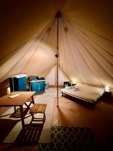 Zelt mit einem Bett und einem Tisch in der Unterkunft Grand tepee glamping pour 2 in Saint-Lyphard