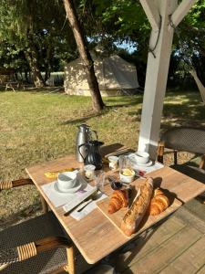 a wooden table with bread and croissants on it at Grand tepee glamping pour 2 in Saint-Lyphard