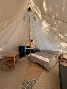 a bedroom with a tent with a bed and a table at Grand tepee glamping pour 2 in Saint-Lyphard