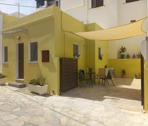 Casa amarilla con patio y mesa en Nisos suite, en Ermoupoli