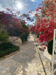 een stenen loopbrug met roze bloemen en planten bij Superior Private Apartment at the Resort in Sarande in Sarandë
