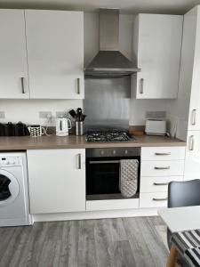 cocina con armarios blancos y fogones en Saint’s Retreat Whitby en Whitby