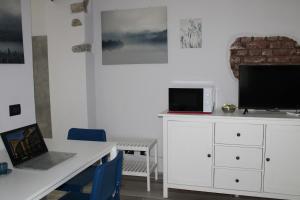 a room with a desk with a laptop and a tv at La luna Blu Malpensa appartamento Lago in Somma Lombardo
