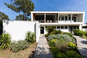 una casa bianca con delle piante davanti di Villa La Vigne - Réf 113 a Lège-Cap-Ferret