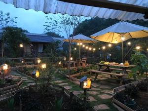 Plum Hill - Moc Chau في موك تشاو: فناء به طاولات ومظلات في الليل
