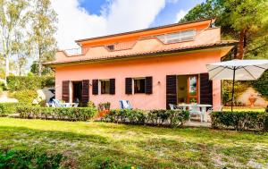 una casa rosa con un paraguas en el patio en Villa Vanna Bilo A - bilocale, en Capoliveri