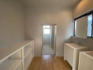 a white bathroom with a sink and a mirror at ikibase Guest House in Iki