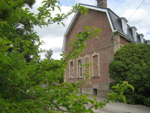 un viejo edificio de ladrillo con árboles delante de él en Le Clos Boutenelle en Éperlecques