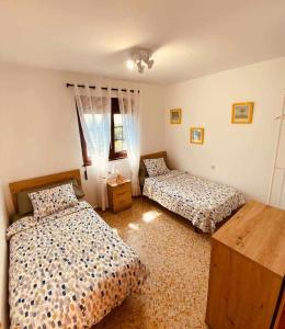 a bedroom with two beds and a wooden table at Casa entre el Mar y la Montaña in Caravia