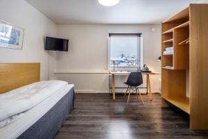 a bedroom with a bed and a desk and a window at HOTEL SØMA Nuuk in Nuuk