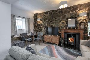 a living room with a stone wall with a fireplace at Felin Traeth Cottage in Rhosneigr