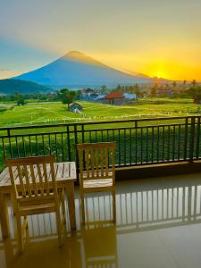 Duas cadeiras e uma mesa numa varanda com um pôr-do-sol em D'uma Amed Homestay em Amed