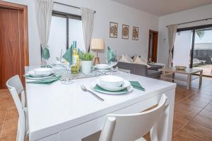 Un comedor con una mesa y sillas blancas. en Casa Rosa, en Playa Blanca