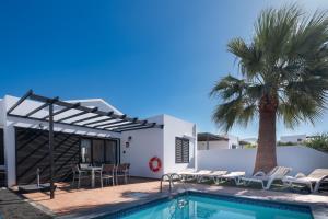 una villa con piscina y palmera en Casa Rosa, en Playa Blanca