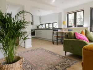 a living room with a green couch and a kitchen at Cherry Orchard Farm in Maidstone