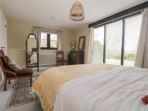 a bedroom with a bed and a chair and a window at Cherry Orchard Farm in Maidstone