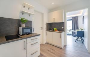 a kitchen with white cabinets and a tv on a counter at Apartments Boddenblick in Sagard