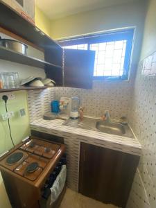 a small kitchen with a stove and a sink at Modern 1-Bedroom Apartment with AC & Parking along Mtwapa Beach Road in Mtwapa