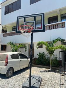 a basketball hoop and a white car parked in front of a building at Modern 1-Bedroom Apartment with AC & Parking along Mtwapa Beach Road in Mtwapa