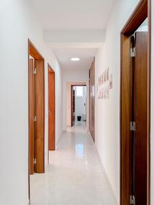 a hallway with wooden doors and a white tile floor at Refúgio Urbano com Acesso Fácil às Praias in Lagos