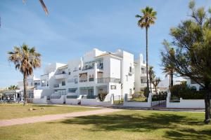a large white building with palm trees in front of it at Barrosamar - Primera línea de playa in Chiclana de la Frontera