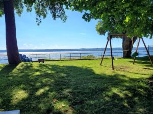 um parque com um baloiço e uma árvore e a água em Le temps d'une île (Maison) - Vue sur le fleuve em Saint-Laurent-de-l'ile d'Orleans