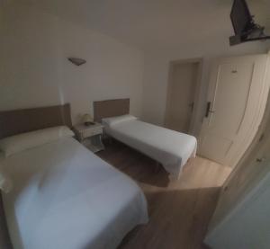 um quarto branco com duas camas e uma porta em Hostal Rural Sositana em Castejón de Sos