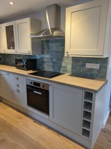 a kitchen with white cabinets and a stove top oven at Sterennyk in Helston